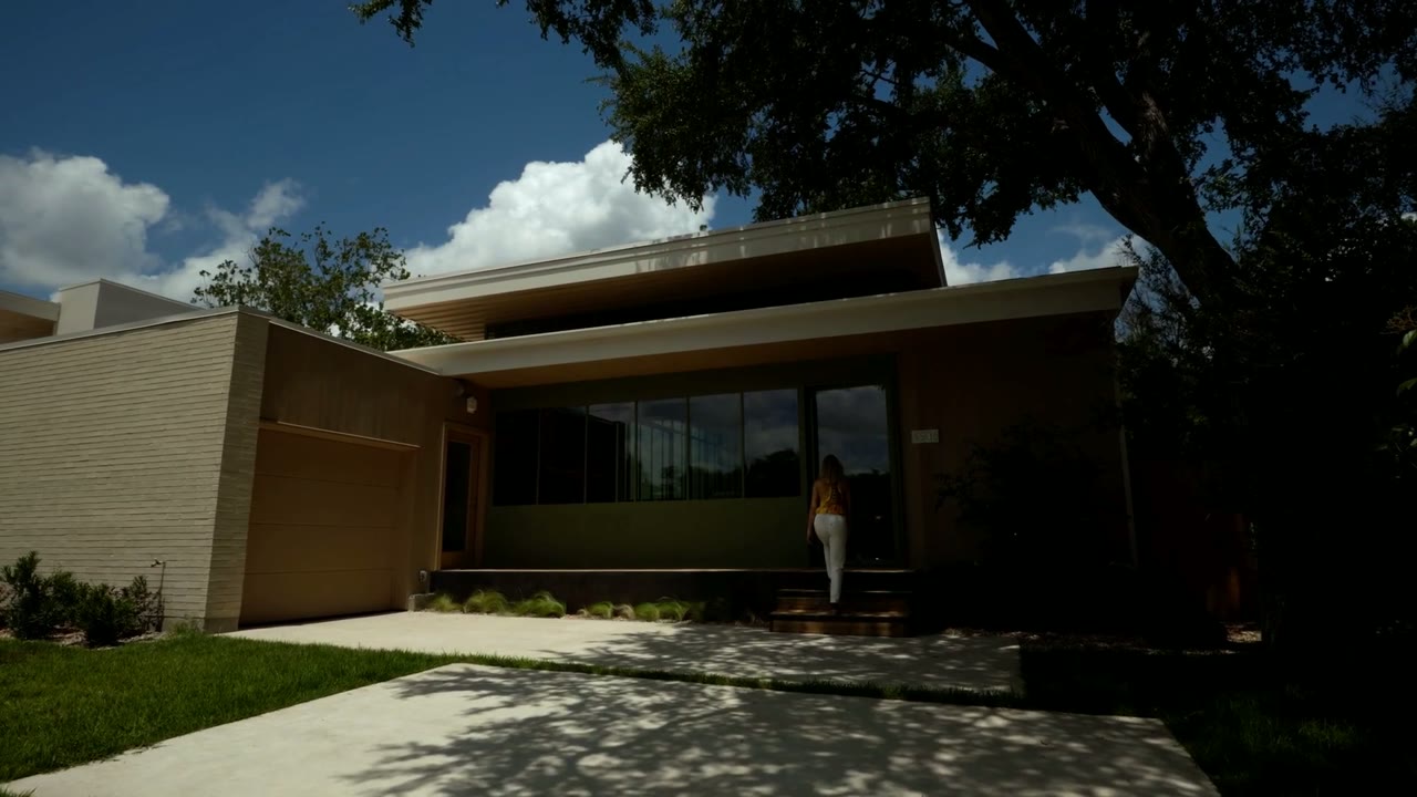A sunlit modern Austin home with someone walking up the front steps